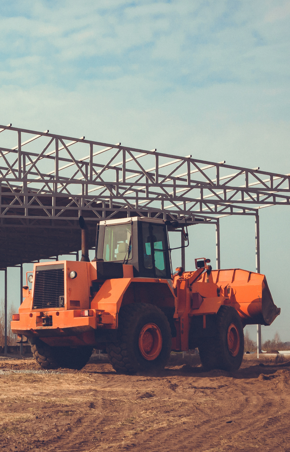 Construction of a large hangar in the countryside with the help of heavy machinery.